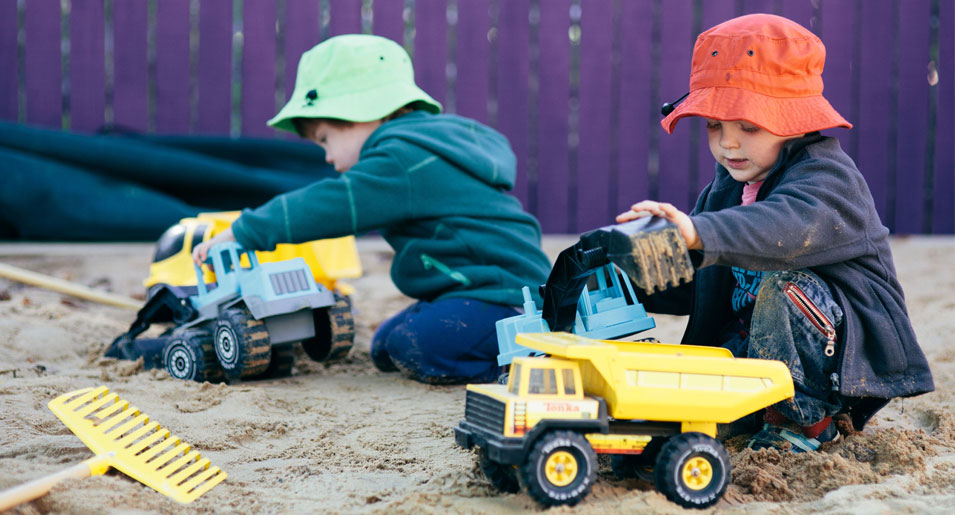 Children playing with trucks in sand